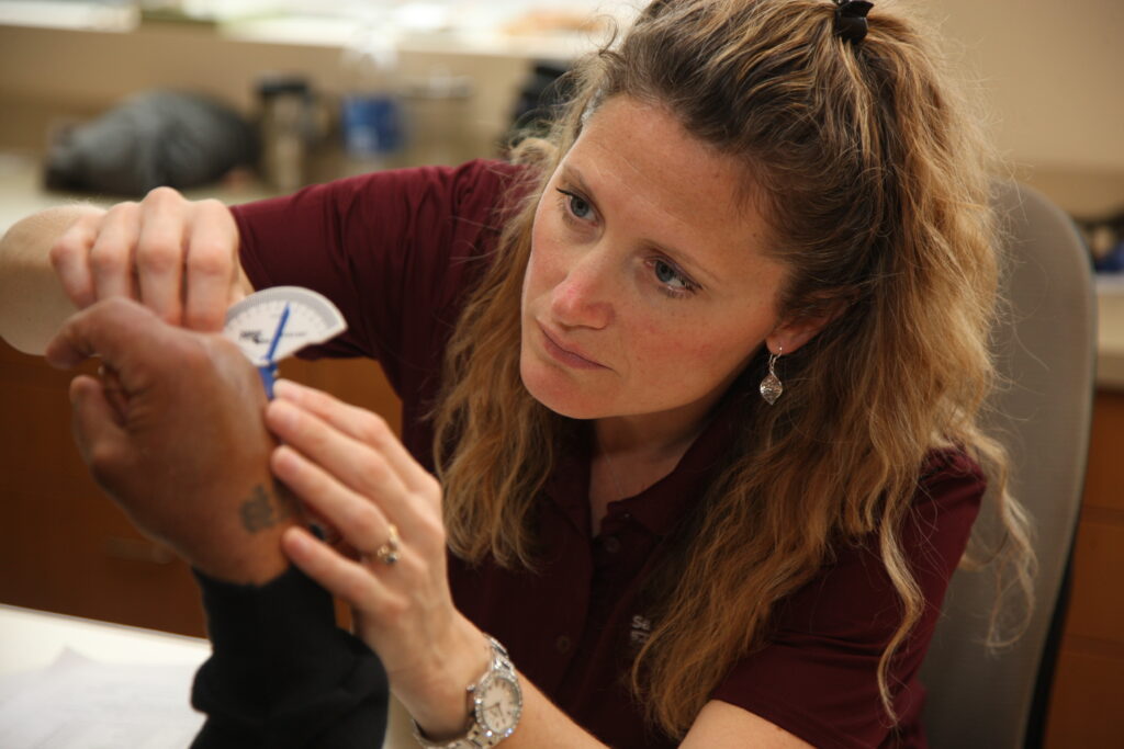 Woman measuring a man's deformed hand during National Occupational Therapy Month